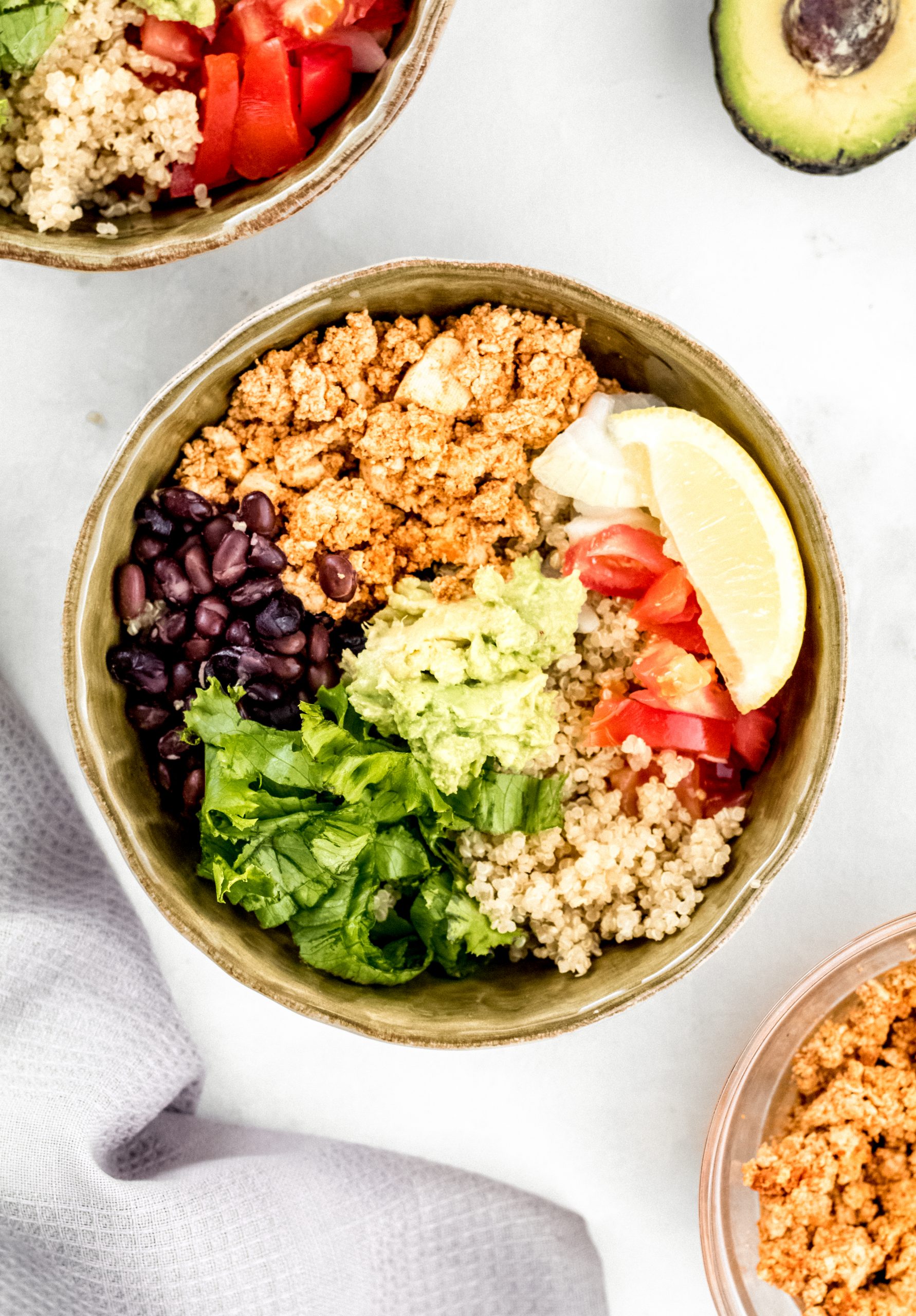 mexican quinoa bowls with tofu sofritas, black beans, onions, tomatoes, lettuce, and guacamole.